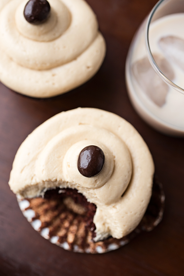 Closeup on an Irish Cream Coffee Cupcake with a bite out of it and a glass of Irish Cream | thecozyapron.com