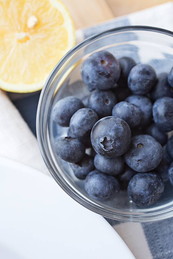 A ramekin of fresh blueberries and a lemon slice for my Blueberry Rolls recipe | thecozyapron.com