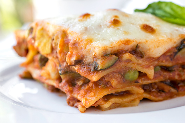 Closeup on a serving of lasagna primavera showing layers of vegetables, pasta, and melted cheese | thecozyapron.com