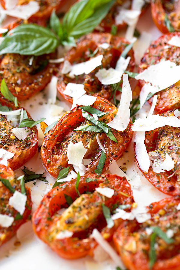 A Closeup view of Succulent Roasted Tomatoes on a white serving platter | thecozyapron.com