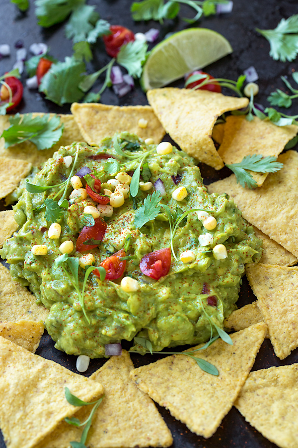 Easy Guacamole served rustically on a platter, surrounded by tortilla chips | thecozyapron.com