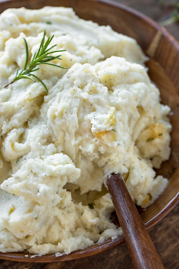 Closeup on a beautiful wooden serving bowl of Roasted Garlic Mashed Potatoes | thecozyapron.com